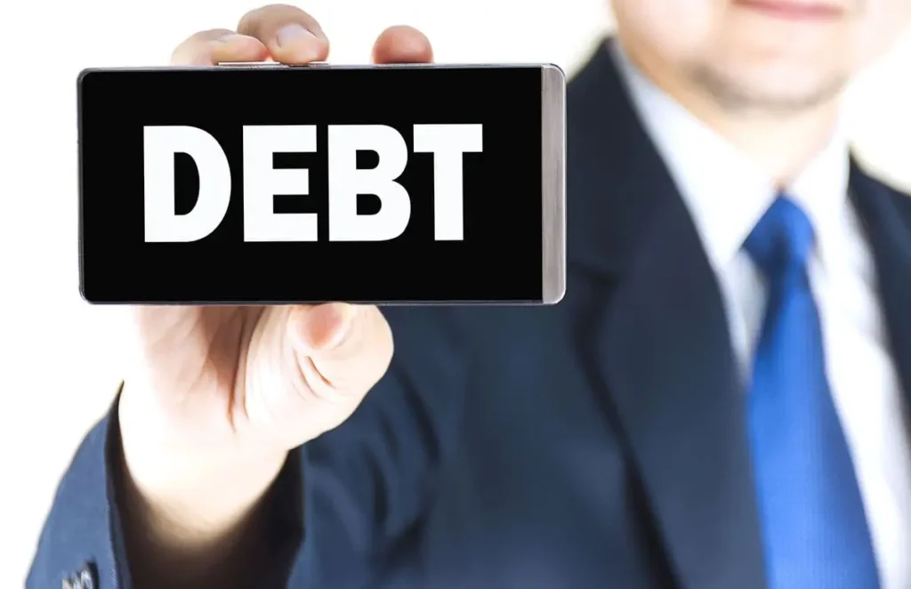 Людина в костюмі тримає смартфон зі словом «БОРГ» на екрані - ілюструє способи стягнення заборгованості