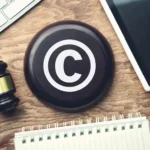 Символ авторського права, оточений суддівським молотком, клавіатурою, планшетом і блокнотом - реєстрація інтелектуальної власності