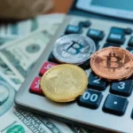 Монети Bitcoin лежать на калькуляторі та купі доларових купюр США - оподаткування криптовалюти в Україні